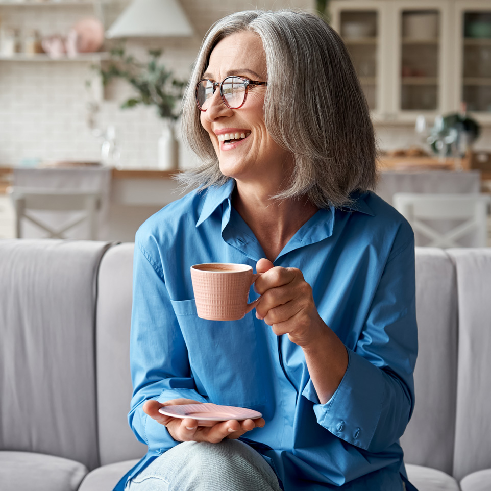 Photo of an older woman with healthy skin enjoying a cup of coffee