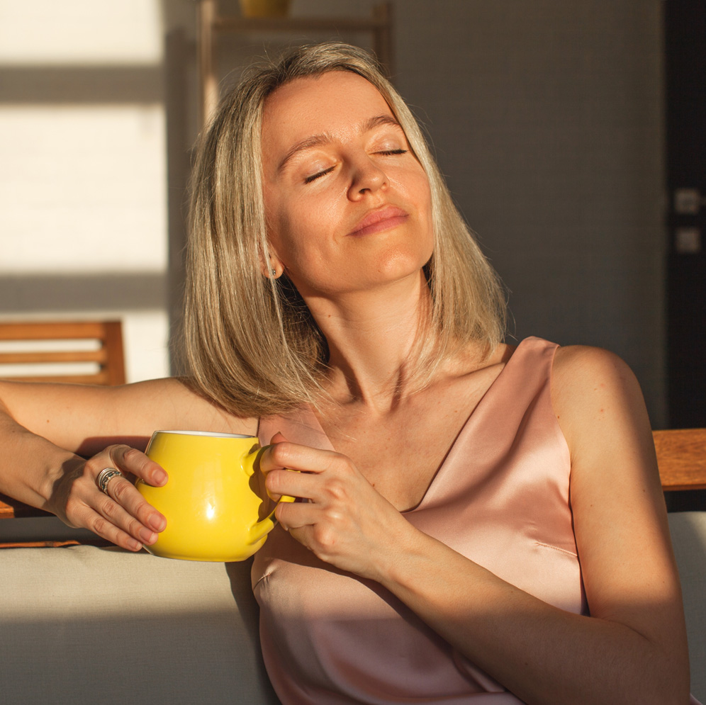 Photo of a middle-aged woman with clear skin relaxing with a cup of coffee