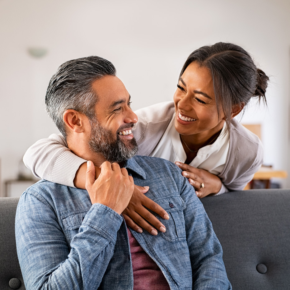 Photo of an older man smiling at a woman with her arm around his shoulder