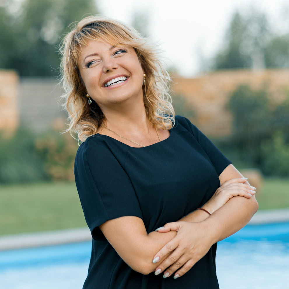 Photo of a confident, smiling middle-aged woman standing by a pool